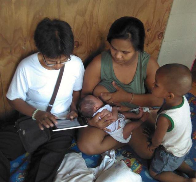 The picture shows a health care worker alongside a woman with a baby and a young boy.