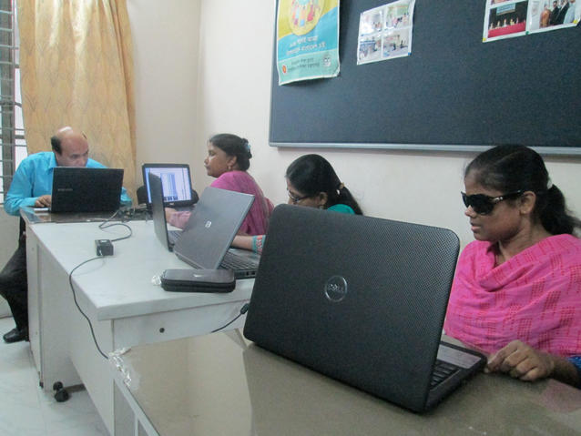 People with visual disabilities are shown working at laptops.