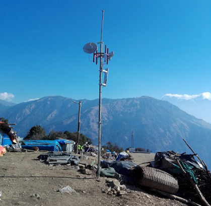 Picture shows a clear day on a mountaintop, with an antenna set up.